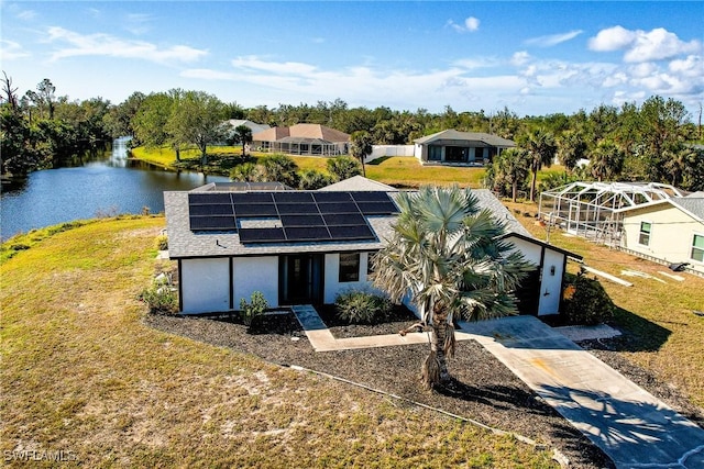 view of front of house with a water view, a front yard, glass enclosure, and solar panels