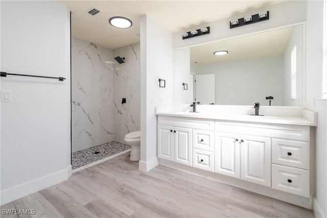 bathroom with vanity, hardwood / wood-style floors, toilet, and tiled shower