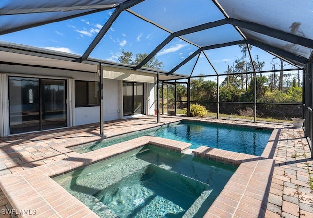 view of pool featuring a patio area, glass enclosure, and an in ground hot tub