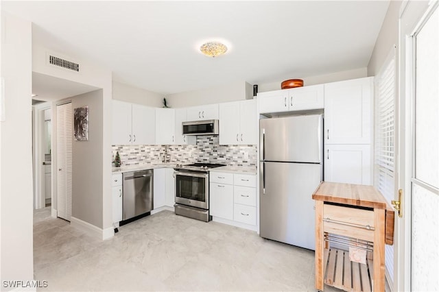 kitchen featuring tasteful backsplash, white cabinets, and appliances with stainless steel finishes