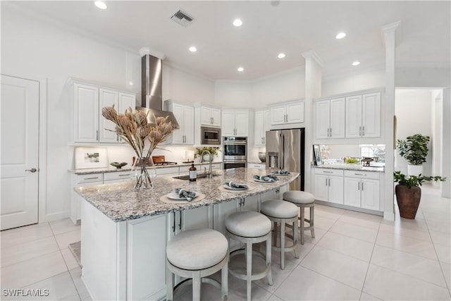 kitchen with a kitchen island with sink, white cabinets, sink, light stone countertops, and stainless steel appliances