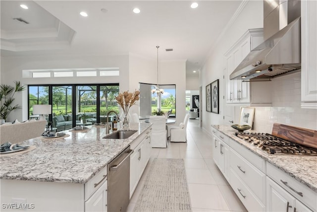 kitchen featuring a large island with sink, sink, wall chimney exhaust hood, white cabinetry, and stainless steel appliances