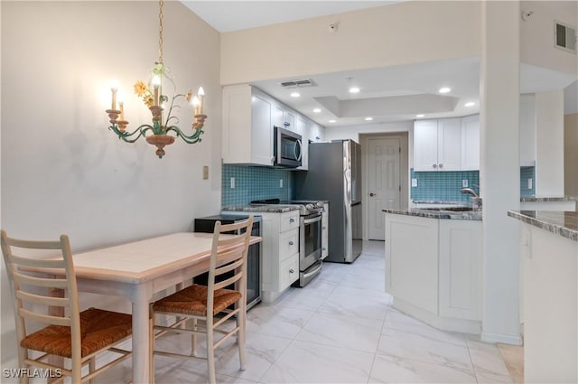 kitchen featuring light stone counters, stainless steel appliances, white cabinets, and decorative backsplash