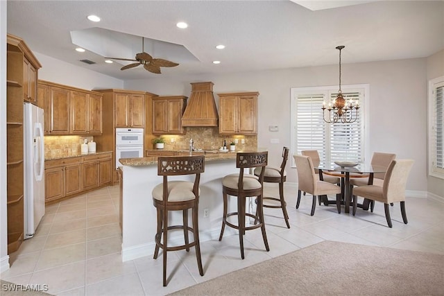 kitchen featuring brown cabinetry, hanging light fixtures, a kitchen bar, and light stone countertops