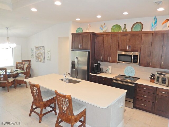 kitchen featuring pendant lighting, sink, an island with sink, a notable chandelier, and stainless steel appliances