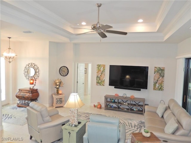 living room featuring ceiling fan with notable chandelier, light tile patterned floors, crown molding, and a tray ceiling