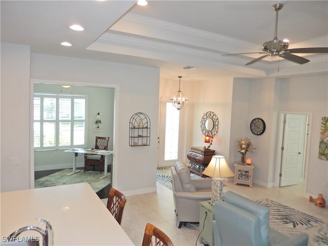 living room with light tile patterned floors, ceiling fan with notable chandelier, a raised ceiling, and ornamental molding