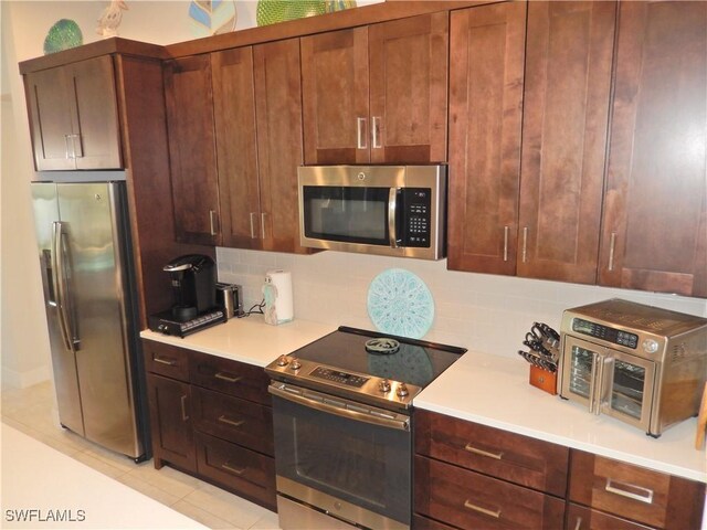 kitchen with backsplash, light tile patterned floors, and stainless steel appliances