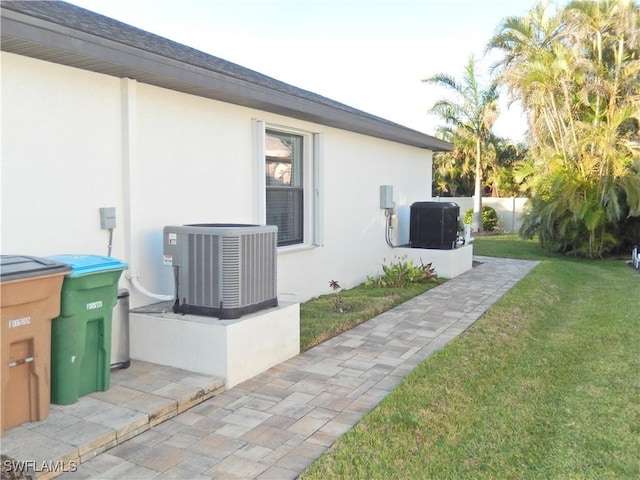 view of side of home featuring a lawn and central AC unit