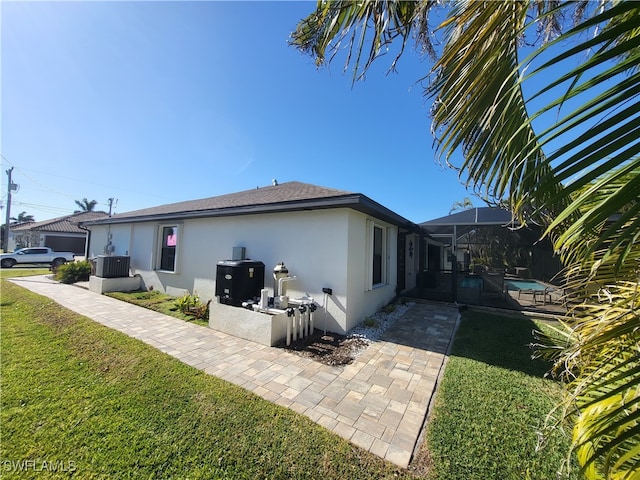 rear view of house featuring a lanai, a lawn, and central AC unit