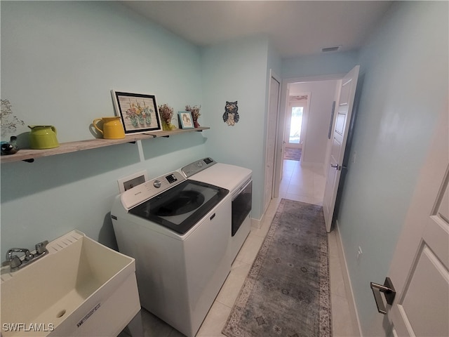 laundry area with separate washer and dryer, sink, and light tile patterned floors