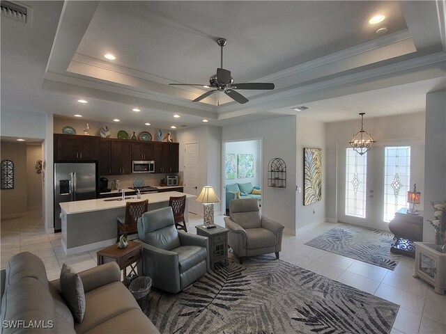 living room with a tray ceiling, crown molding, and light tile patterned floors