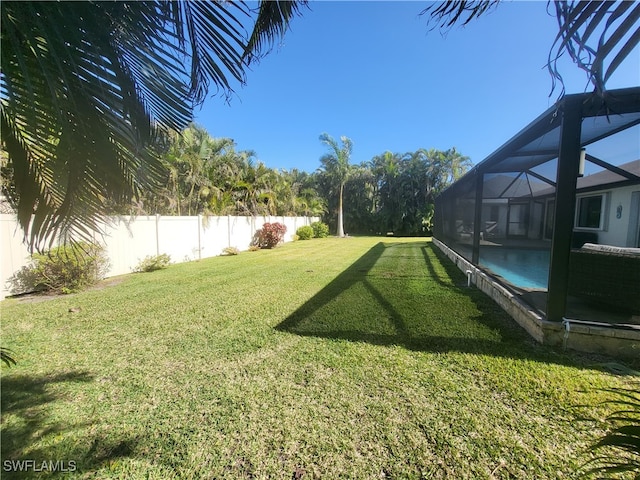 view of yard featuring a fenced in pool and glass enclosure