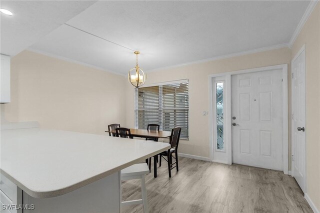 dining room featuring crown molding, an inviting chandelier, and light hardwood / wood-style flooring