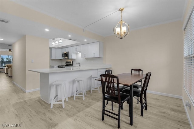 dining room featuring a notable chandelier, crown molding, a wealth of natural light, and light wood-type flooring