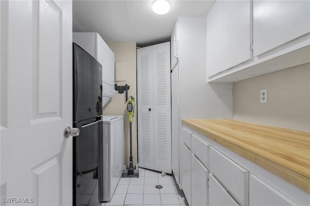 laundry room featuring light tile patterned flooring, a textured ceiling, and stacked washing maching and dryer