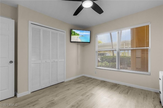 unfurnished bedroom with light hardwood / wood-style flooring, ceiling fan, and a closet