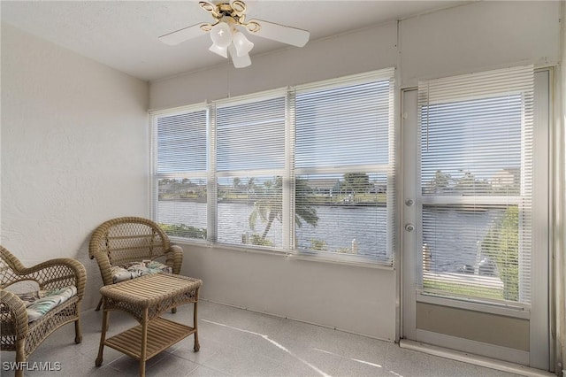 sunroom featuring ceiling fan and a water view