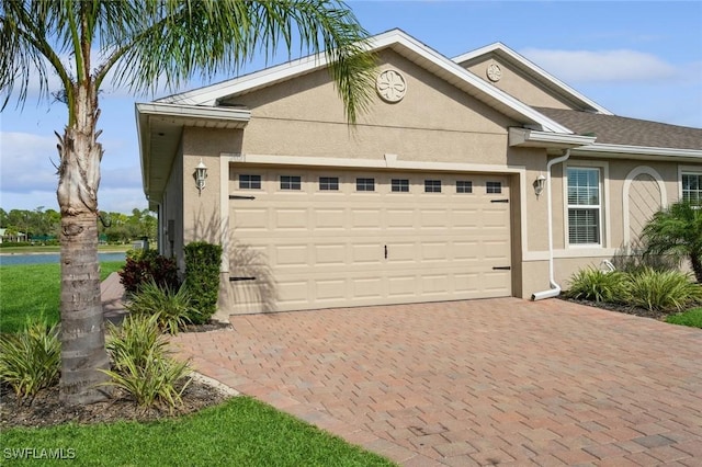 single story home featuring stucco siding, decorative driveway, and a garage