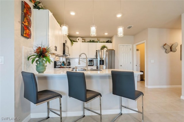 kitchen with decorative backsplash, light tile patterned floors, appliances with stainless steel finishes, white cabinetry, and a breakfast bar area