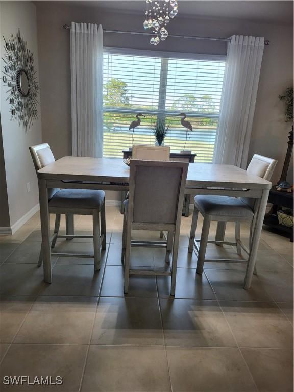 tiled dining space featuring a wealth of natural light and an inviting chandelier