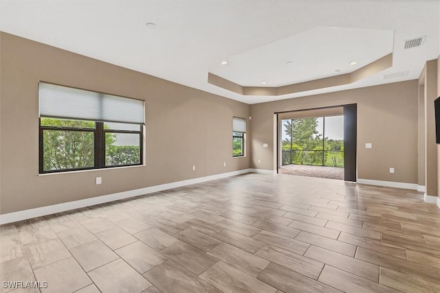 unfurnished room with a tray ceiling and a healthy amount of sunlight