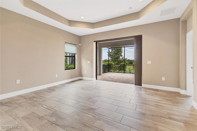 spare room featuring a tray ceiling and a healthy amount of sunlight