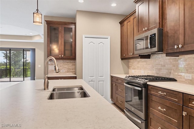 kitchen with tasteful backsplash, appliances with stainless steel finishes, sink, and decorative light fixtures