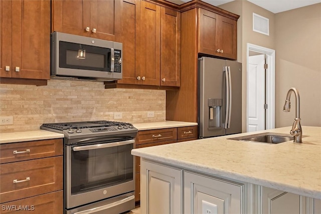 kitchen featuring light stone counters, backsplash, sink, and appliances with stainless steel finishes