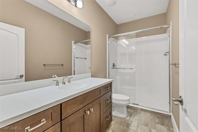 bathroom featuring vanity, hardwood / wood-style floors, a shower with shower door, and toilet