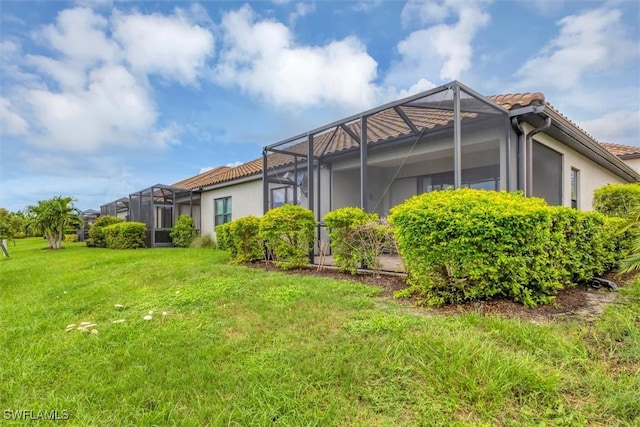 view of home's exterior featuring a lawn and glass enclosure