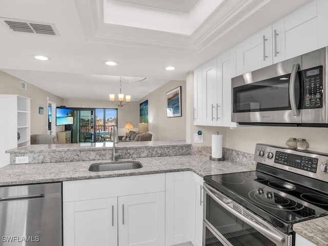 kitchen with white cabinetry, sink, an inviting chandelier, a raised ceiling, and appliances with stainless steel finishes