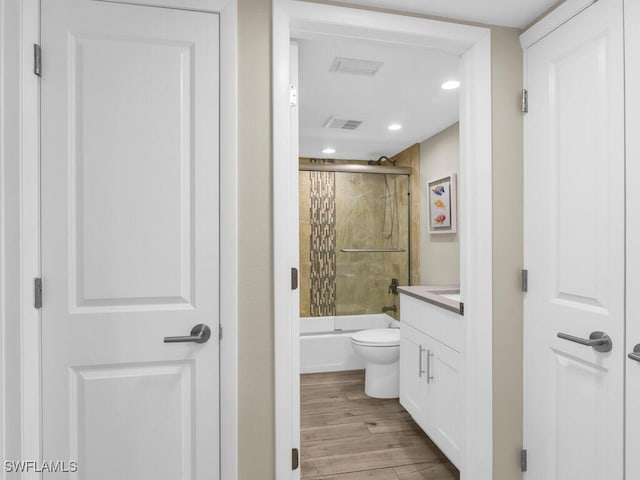 full bathroom with hardwood / wood-style flooring, vanity, toilet, and shower / bath combination with glass door