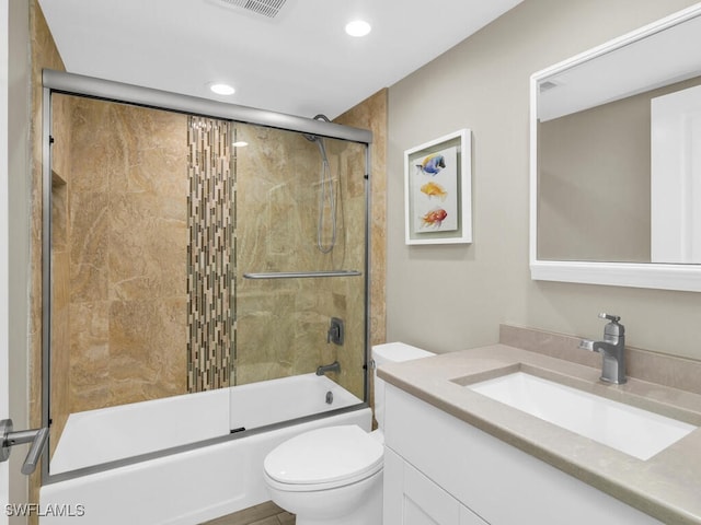 full bathroom featuring vanity, bath / shower combo with glass door, and toilet