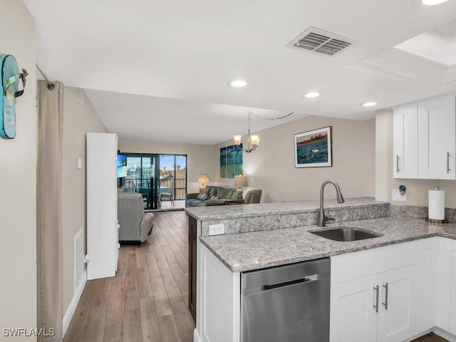 kitchen featuring kitchen peninsula, stainless steel dishwasher, sink, an inviting chandelier, and white cabinetry