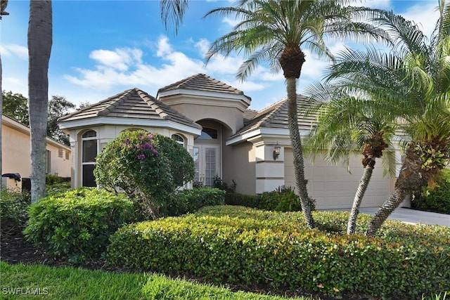 view of front facade featuring a garage, concrete driveway, stucco siding, and a tiled roof