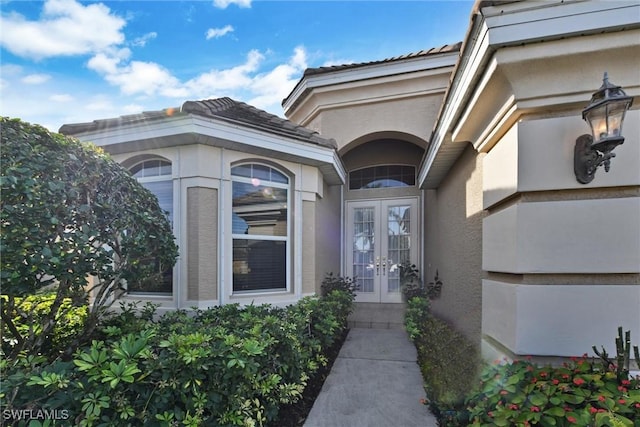 doorway to property featuring a tiled roof, french doors, and stucco siding