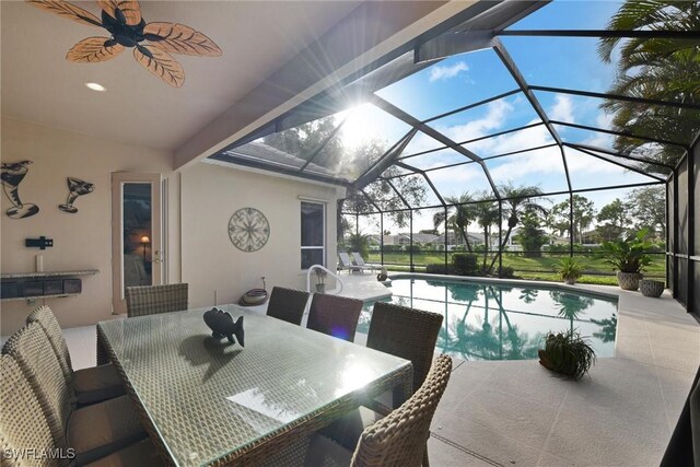 view of swimming pool with glass enclosure, ceiling fan, and a patio area