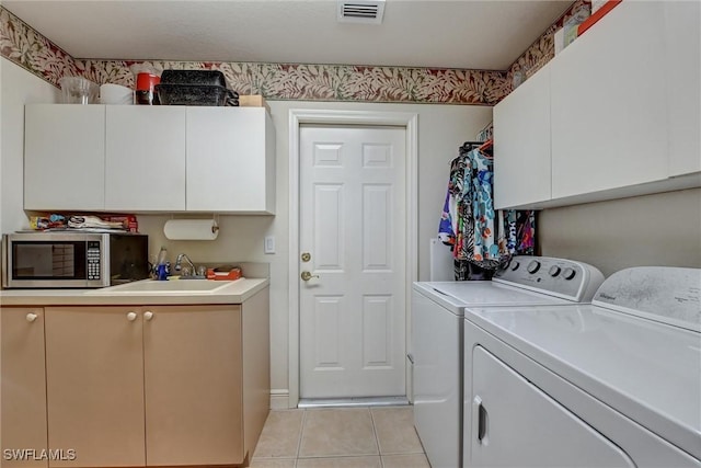 laundry area featuring washer and clothes dryer, light tile patterned flooring, cabinets, and sink