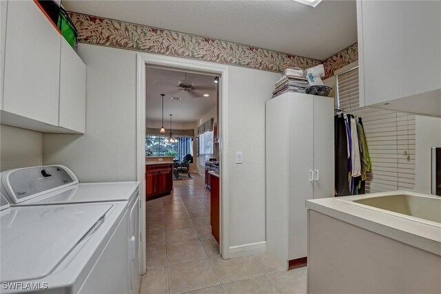 laundry room with cabinets, ceiling fan with notable chandelier, sink, light tile patterned floors, and washing machine and clothes dryer