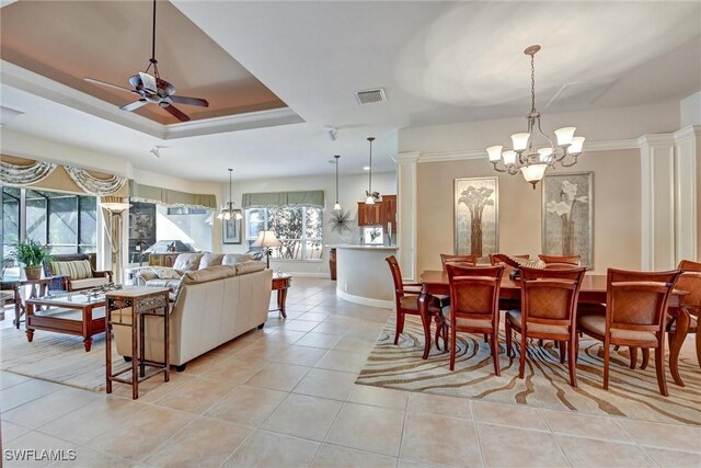 dining space with ceiling fan with notable chandelier, a raised ceiling, and light tile patterned flooring