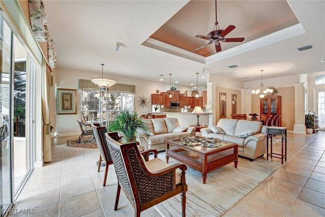 living room featuring a raised ceiling, light tile patterned flooring, and ceiling fan with notable chandelier