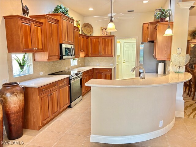 kitchen with kitchen peninsula, decorative backsplash, stainless steel appliances, light tile patterned floors, and decorative light fixtures