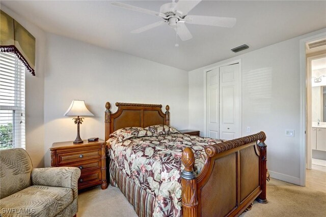 bedroom featuring a closet, ceiling fan, light colored carpet, and ensuite bathroom