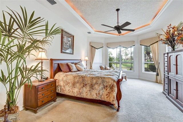 bedroom featuring ceiling fan, a raised ceiling, a textured ceiling, and light carpet