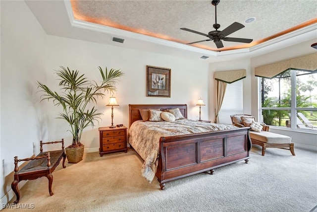 bedroom with a raised ceiling, ceiling fan, light carpet, and a textured ceiling