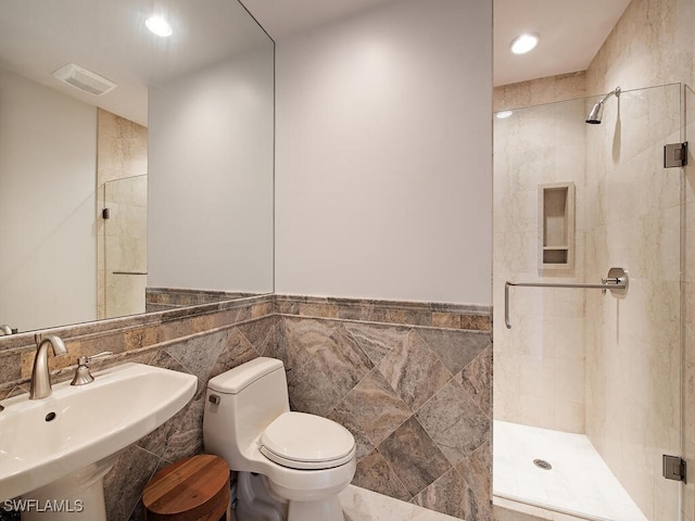 bathroom featuring a shower with door, tile walls, and sink