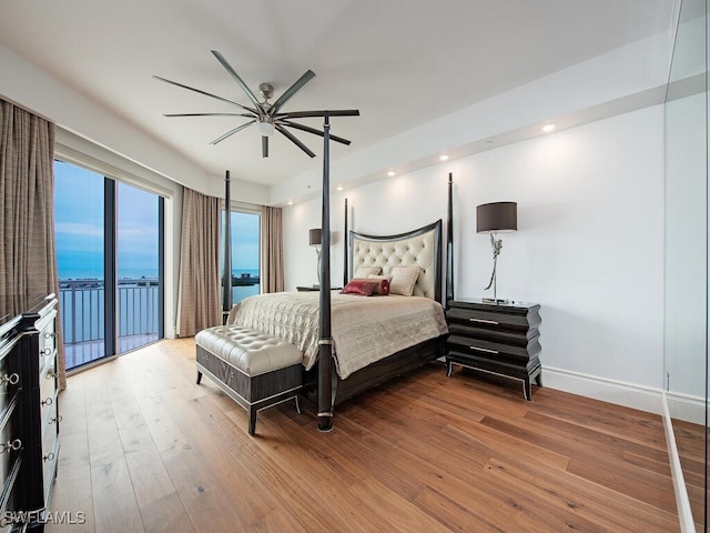 bedroom with access to outside, a water view, ceiling fan, and hardwood / wood-style flooring