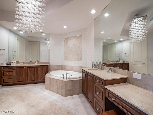 bathroom with tiled bath, vanity, and an inviting chandelier