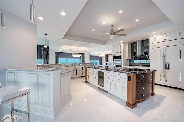 kitchen featuring a raised ceiling, white cabinetry, and decorative light fixtures